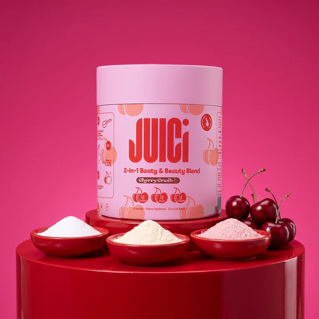 JUICi cherry crush tub on a cherry-red stand with bowls of creatine, collagen and BCAA powders and fresh cherries